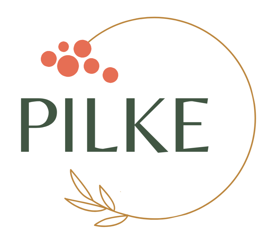 Logo, jossa lukee isolla PILKE. Tekstiä ympäröi kaari. Kaaren päässä on viisi pientä punaista palloa rykelmässä i-kirjaimen päällä. Toisessa päässä kaarta on neljä beigeä lehteä.